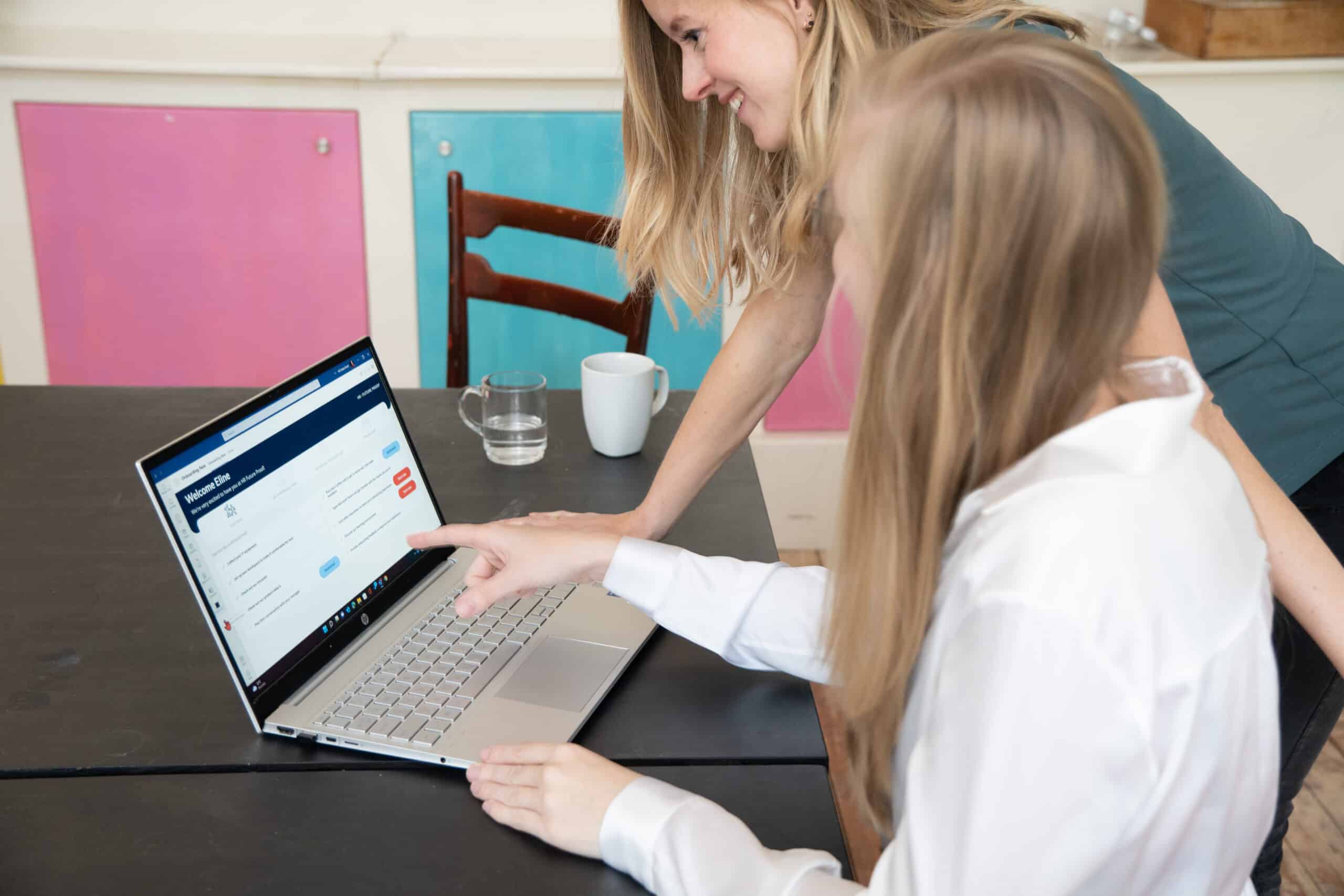 Twee collega's bekijken een slimme HR app op een laptop